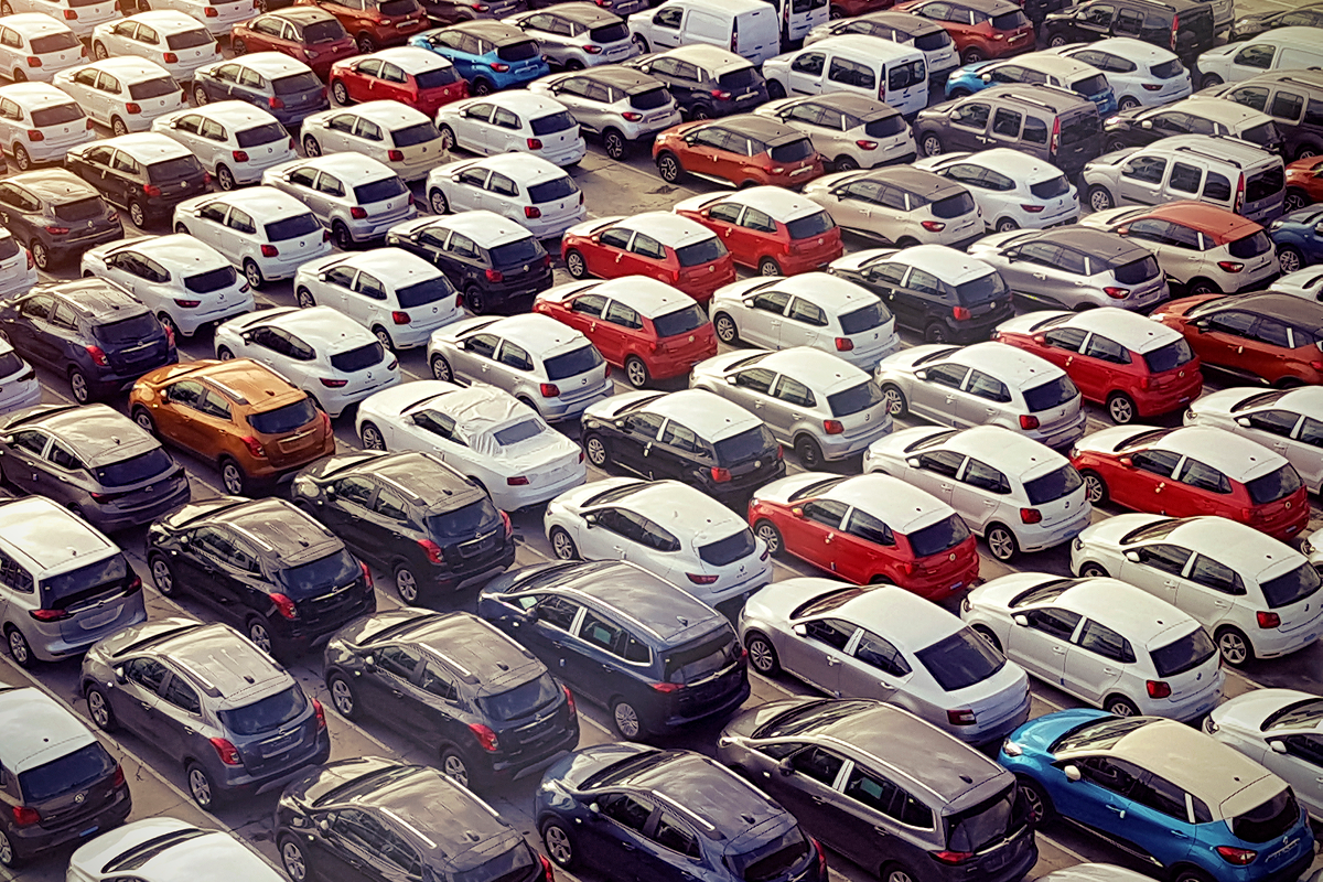 Aerial view of a crowded parking lot filled with various colored cars, tightly parked in rows.